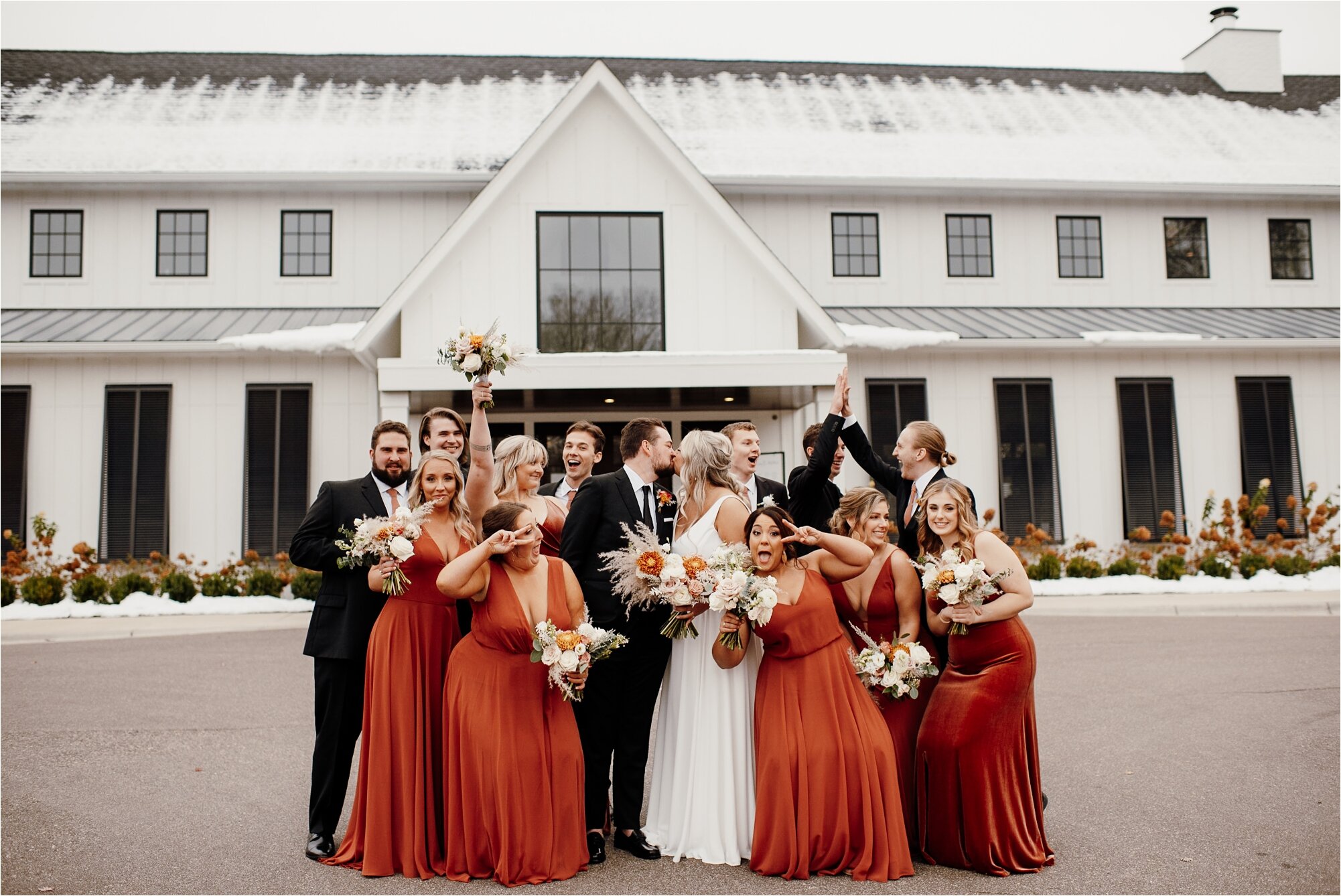  wedding party celebrating couple on their wedding day as the bride and groom kiss 